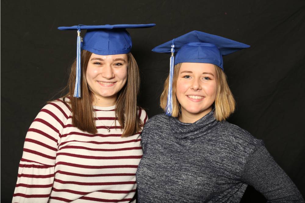 two friends in graduation caps smiling